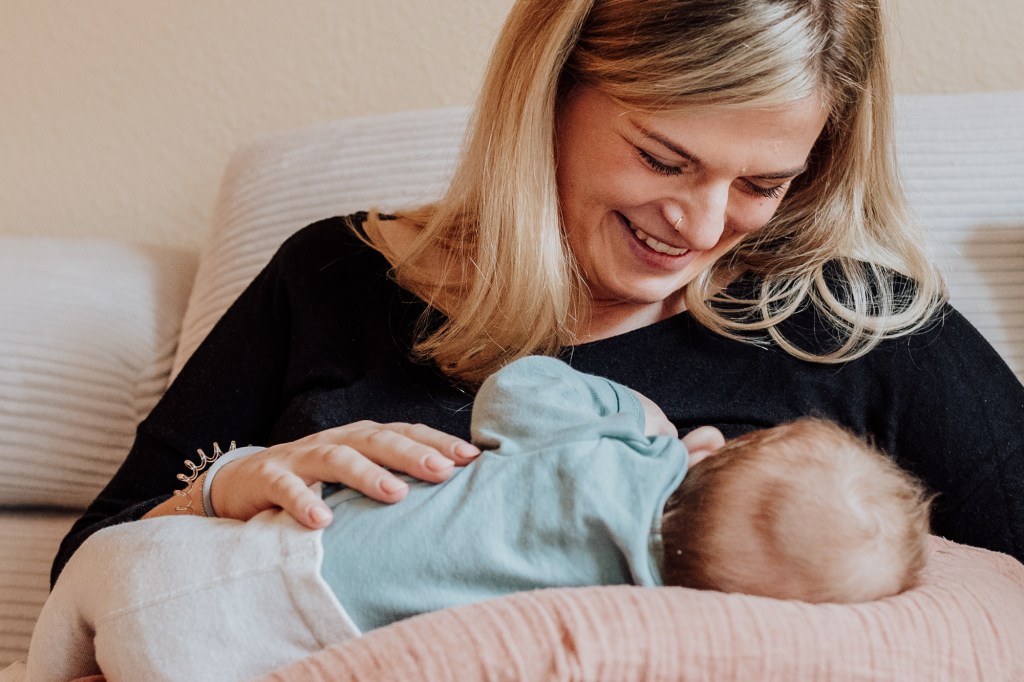 Mutter lacht Neugeborenes an