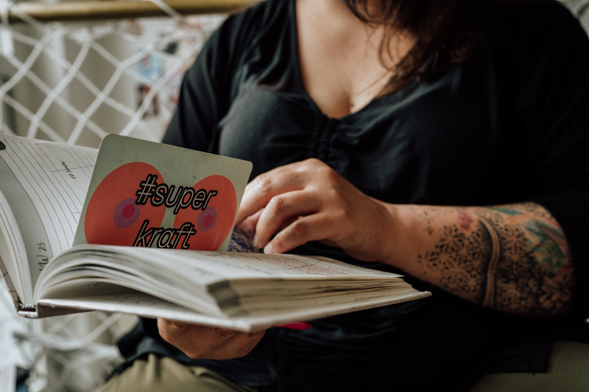 Hebamme hält Terminplaner in Hand mit einer Postkarte mit der Aufschrift "superkraft"